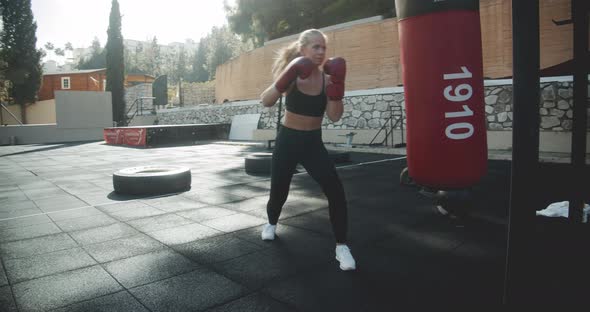 Woman In Sportswear Boxing Punching Bag In Outdoor Gym