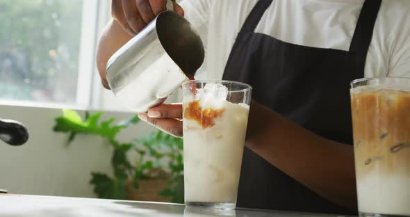 Mid section of african american male barista making coffee using coffe machine at cafe