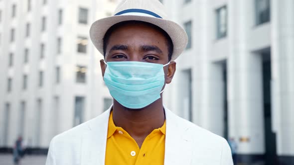 African American man in blue disposable face mask looks straight standing