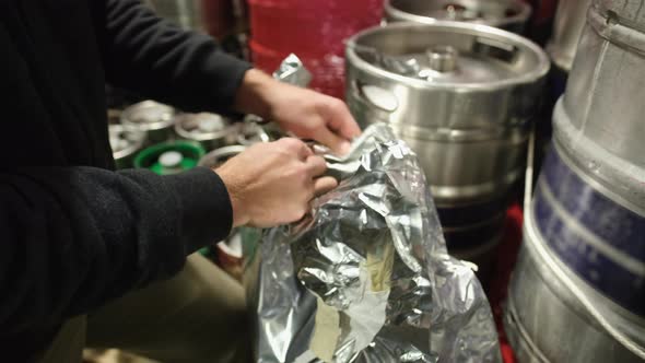 Caucasian Male Hands Opening a Bag of Dried Hops for Beer Brewing