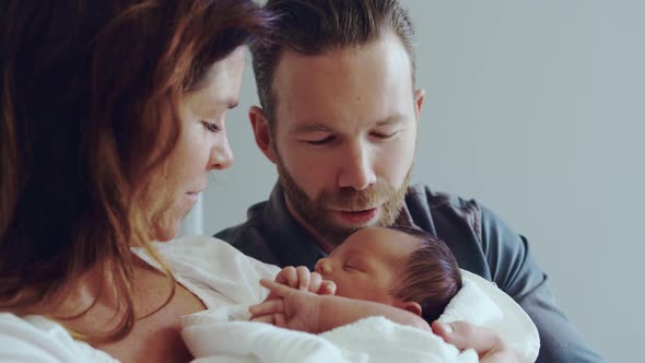 Front view of Caucasian couple holding their newborn baby in the ward at hospital