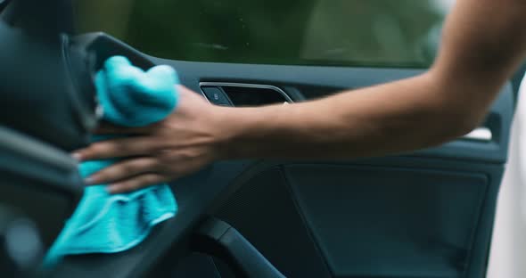 Professional Auto Cleaning Service. Worker Hands Spraying and Wiping Door Inside of Vehicle Salon
