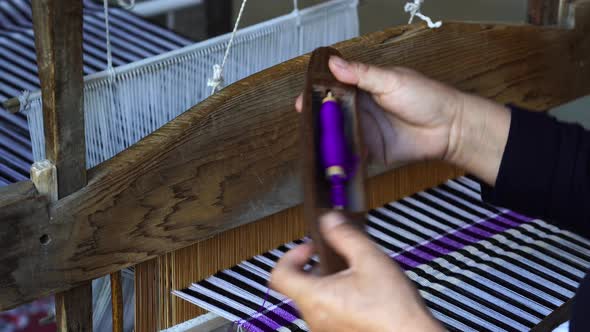 Hands of a woman work on weaving loom machines in a mountain village, Vietnam