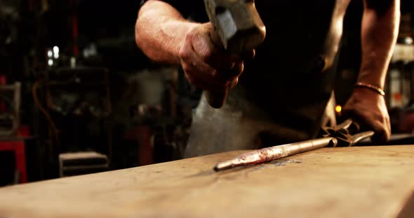 Mid-section of blacksmith working on a iron rod