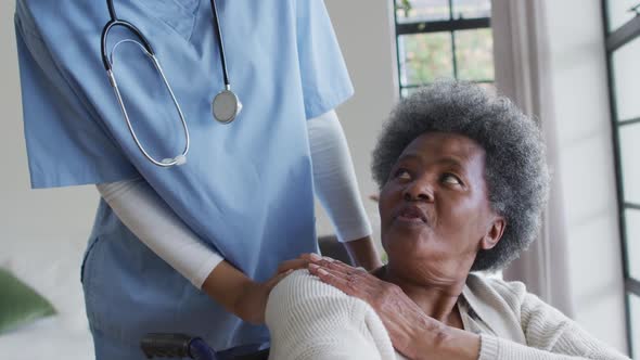 Caring african american female doctor helping senior african american female