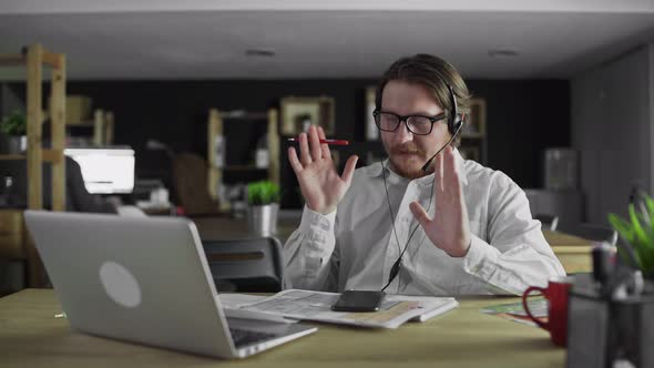 Manager in Headphones Is Working on Laptop at the Office