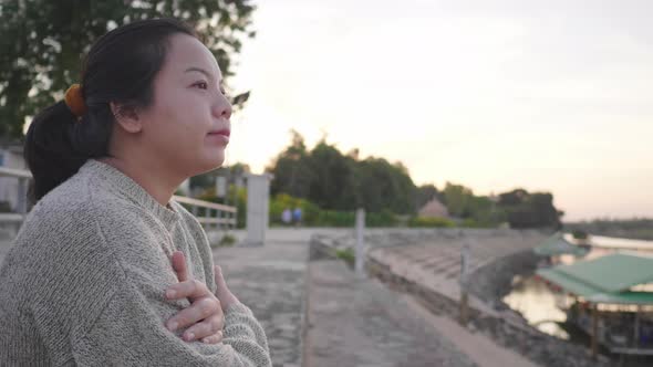 Asian woman sitting and getting good weather by the river