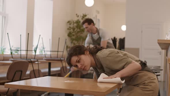 Woman Cleaning Table in Cafe