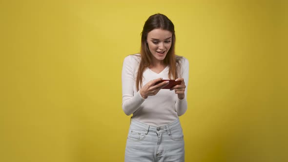 Slender Woman in White Body or Sweater Holds Red Phone in Her Hands and Wins Match or Bet