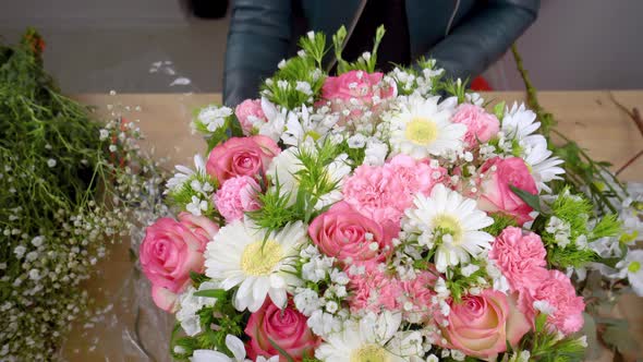 Close-up of the hands of a female florist packing a beautiful composition