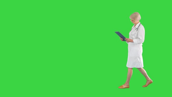 Female Senior Therapist Walking with a Tablet with Some Papers on a Green Screen Chroma Key