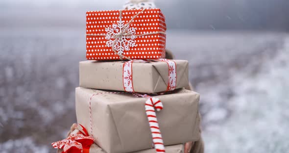 Portrait of a Happy Woman with Gift Boxes on the Snowy Field