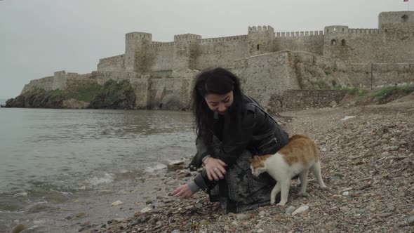 Young and beautiful girl collecting stones on the seaside in front of a castle.