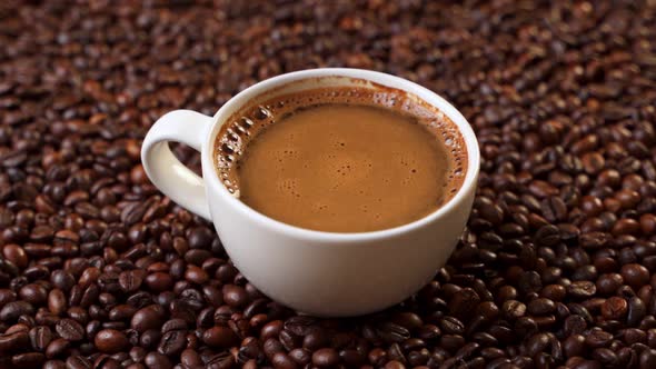 Side View of White Cup of Black Coffe on Coffee Beans