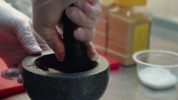 Cook Prepares the Seasoning for the Salad in a Mortar