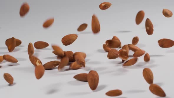 Almonds falling onto a white surface in slow motion