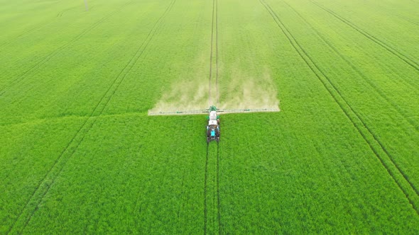 Aerial Video of Tractor Spraying Soil and Young Crop in Springtime in Field