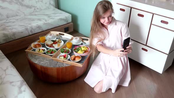 Blogger Woman Make Selfie Photos on Smartphone with Breakfast in Hotel Room