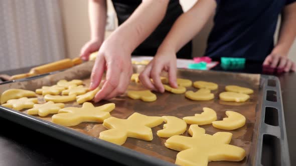 Closeup of a Woman and a Boy's Hands Laying Out Different Shapes of Dough on a Baking Tray