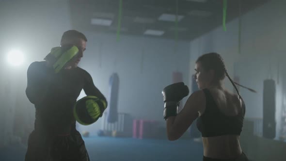 Female Fighter Trains His Fast Punches Punching Focus Mitts Training Day with a Man Coach in Boxing