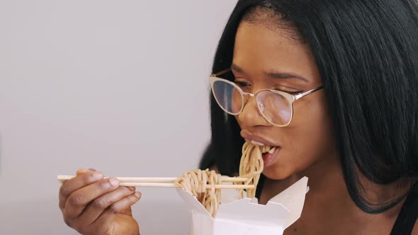 African American Woman Eating Takeaway Noodles at Home