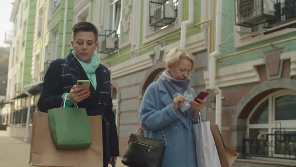 Two Mature Women Obsessed with Phones During Shopping Leisure Outdoors