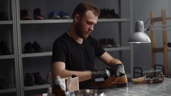 Hand Held Shot of Shoemaker Untying Shoelaces on Worn Light Brown Leather Shoes to Be Repaired