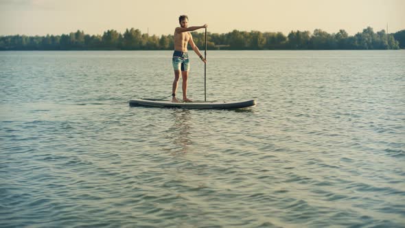 Man Sup Surfing.Standup Puddle Board. Sup Floating.Travel Paddles Paddleboard.Watersport.Surfboard.