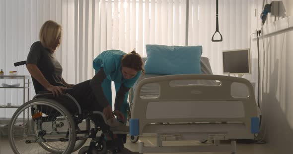 Nurse Taking Senior Woman Patient in Wheelchair at Hospital Ward