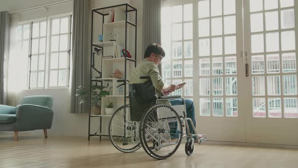 Man Sitting In A Wheelchair Reading Book Near Door In The House