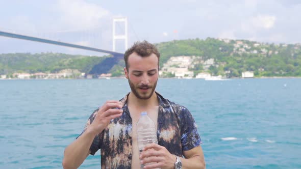 The man who tosses the water in the air and opens it and drinks it. alt