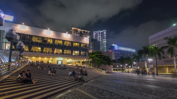 People Sitting on the Stairs Near Hong Kong Cultural Centre with Palms and Towers on Background
