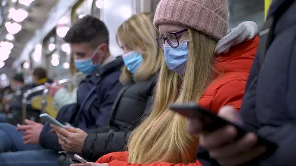 Masked Young People Busy on Phones in Subway Train