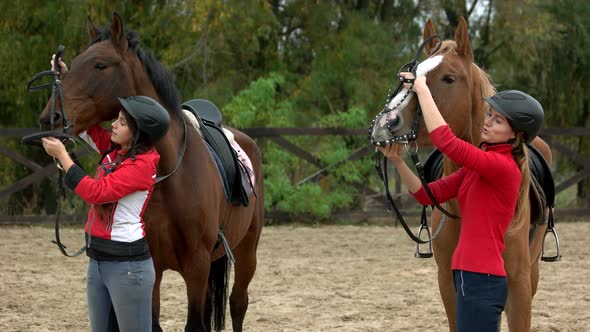 Two Women Preparing Horses for Riding at Farm