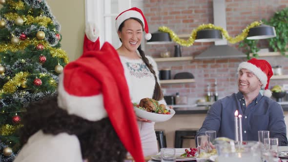 Happy group of diverse friends in santa hats celebrating meal at christmas time