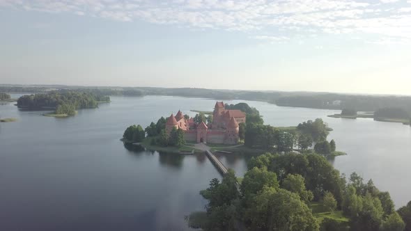 Aerial pan up view of medieval Trakai castle on island in lake Galve at sunrise summer Lithuania