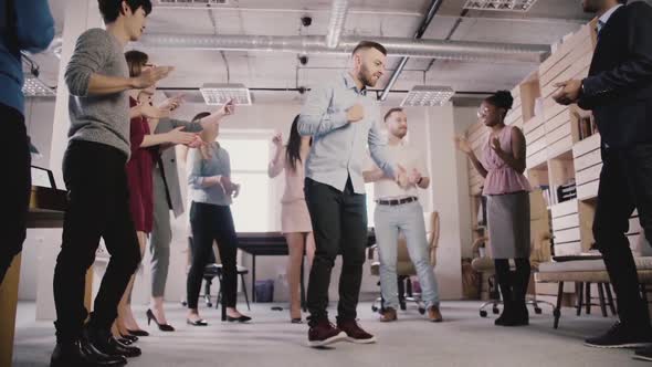 Excited Multiethnic Business People Dance in Circle at Office Teambuilding Party, Celebrating