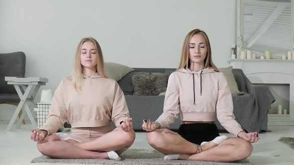 Two friends are sitting in home room in Lotus position