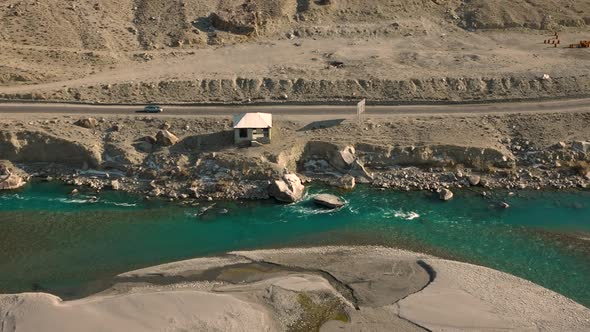 Turquoise blue water of Ghizer river flowing through forest in Gahkuch surrounded by Hindu Kush moun