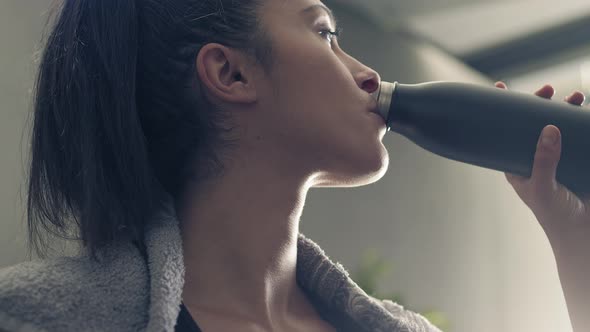 Fitness Woman Drinking From Sport Bottle During a Workout Pause at Home or Gym. Close Backlit