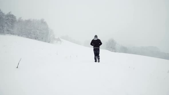 Anonymous man walking on snowy path