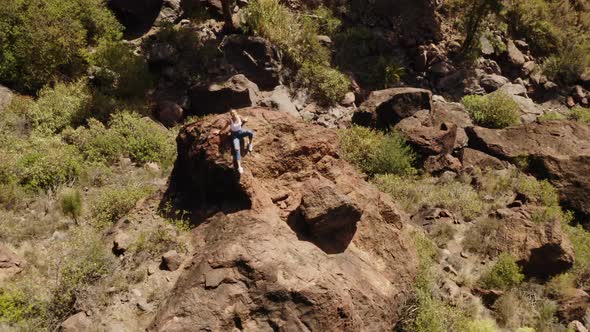 Gorgeous Female Sitting on Boulder Under the Sun