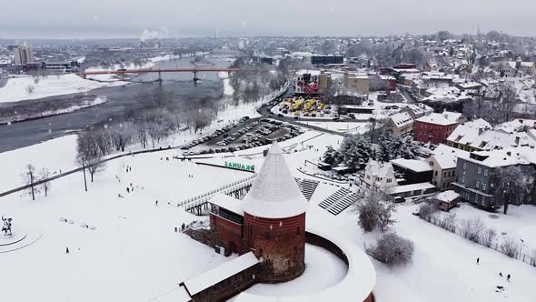 Kaunas Castle covered in snow during snowfall, aerial ascending view