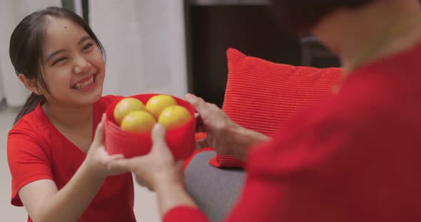 Happy Asian Girl Giving Her Grandmother Orange for Chinese New Year Blessing Gift.