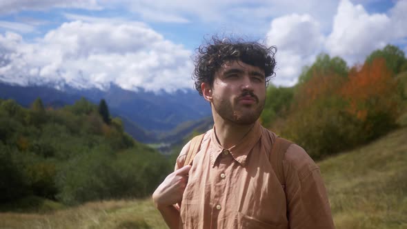 Portrait of a Young Curlyhaired Guy Who is Looking at a Landscape with Beautiful Mountain Nature