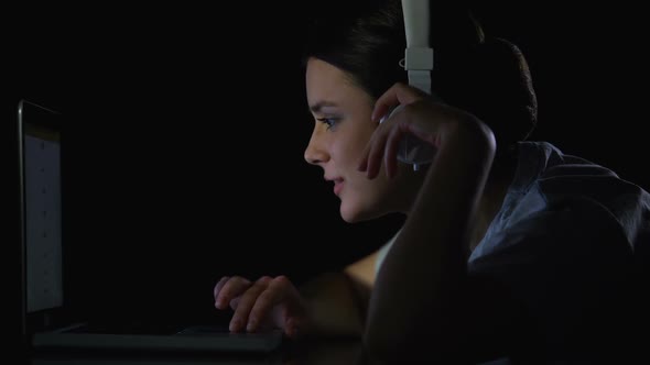 Young Girl Listening to Music in Headphones Scrolling Social Networks on Laptop