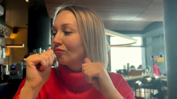 Blonde Woman Sits in a Coffee House in a Good Mood and Dances