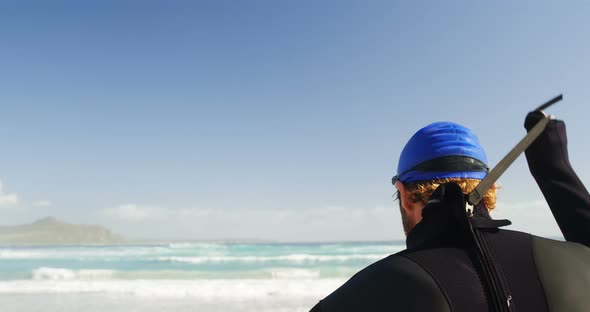 Male surfer standing in the beach 