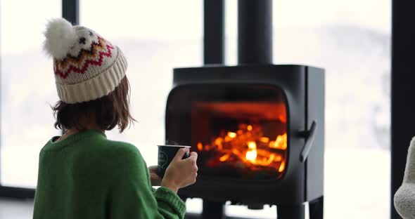 Woman with Hot Drink By the Fireplace in Winter