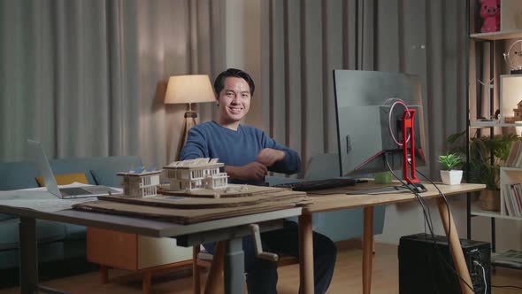 Male Engineer With The House Model Smiling And Crossing His Arms To The Camera While Working